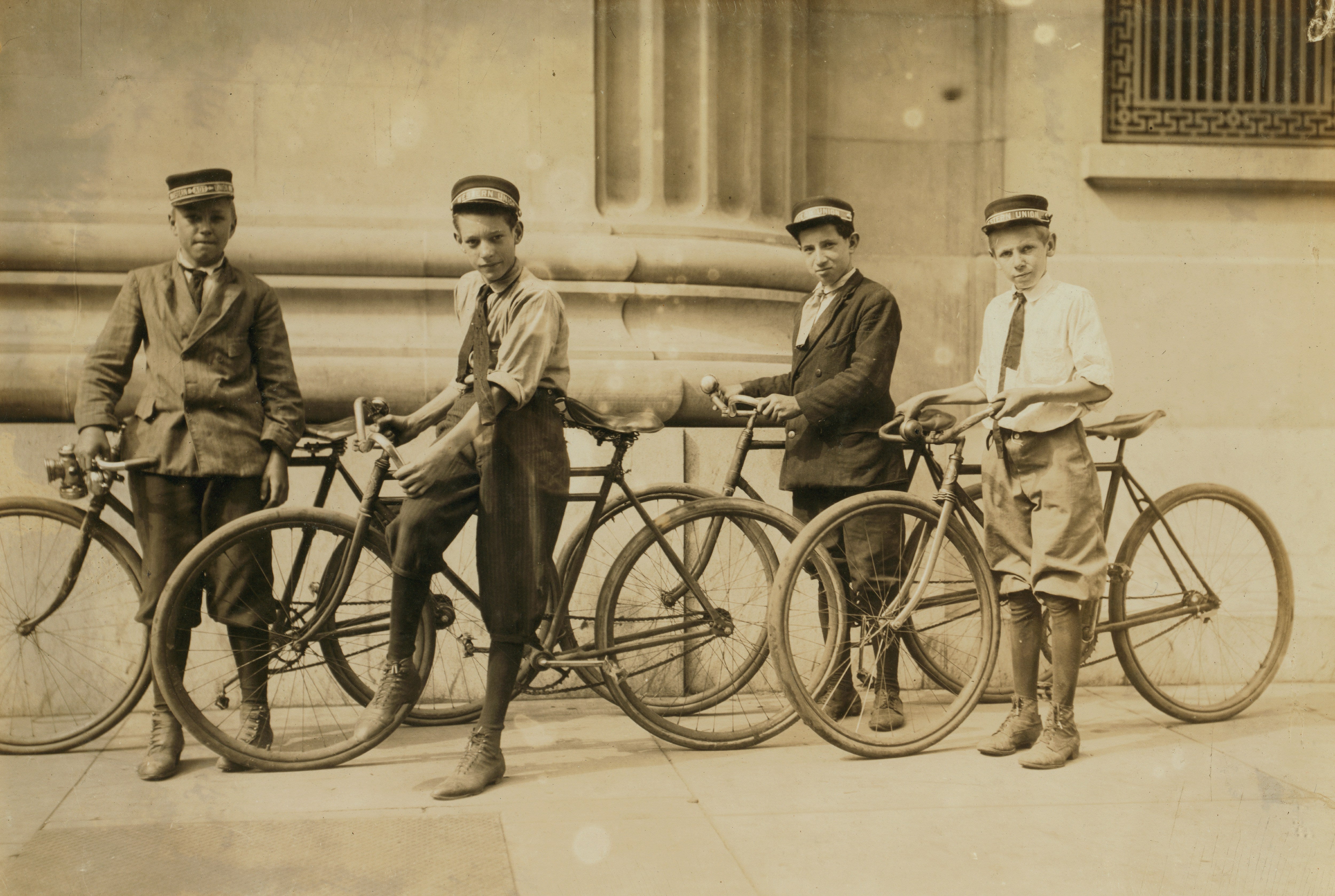 Sepia photo of four white telegraph delivery boys with bicycles