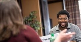 Student smiling at professor with back turned sitting across from them