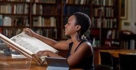 Student reading pages of a large book