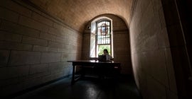 student sitting at desk beside stained glass window inside cathedral
