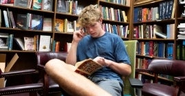 Student reading surrounded by bookshelves